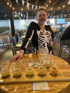 Hannah Legacy, Tasting Room Manager, Mike Hess Brewery with Beer Samples Dressed for Halloween