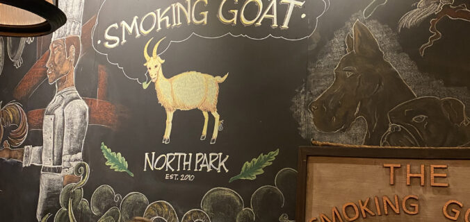 Chalkboard with pictures of goats and The Smoking Goat written on it at the entrance