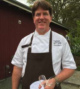 Chef Vincent Nattress of Orchard Kitchen Standing In Front of the Red Farmhouse