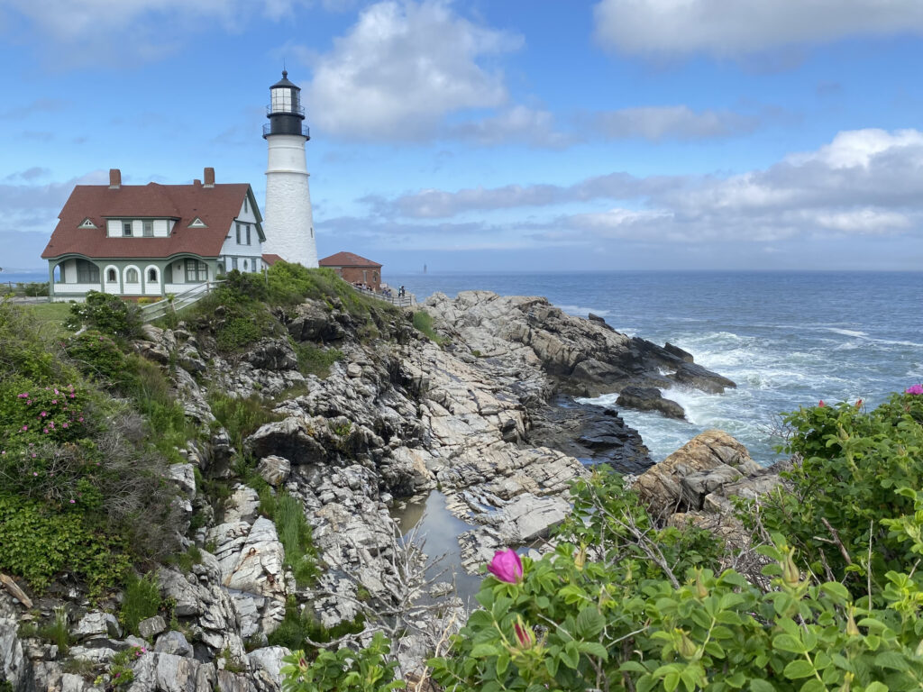 Portland Head Lighthouse on steep rocky cliff overlooking a wild ocean