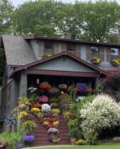 Rich West home covered with container plants hanging and all across the front steps