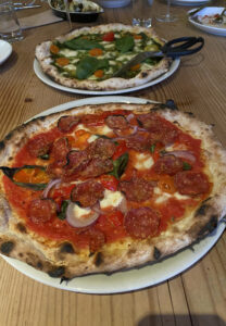Two pizzas at Pizzeria Bruciato, one with tomato sauce and one with dates and prosciutto  