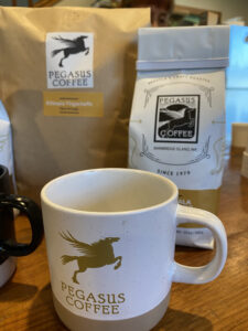 Bags of coffee and Pegasus coffee mug with its signature unicorn on the mug