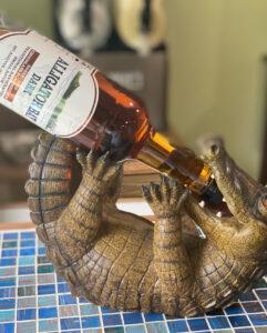 Ceramic alligator holding a bottle of Alligator Bay Distillers Rum