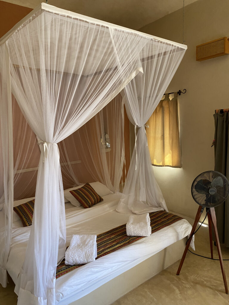 Bedroom with Queen bed and surrounded by mosquito netting with a fan to bring in air from outside