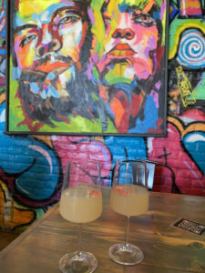 Dija Mara, colorful Balinese inspired restaurant with two lychee cocktails with brilliant art in the background