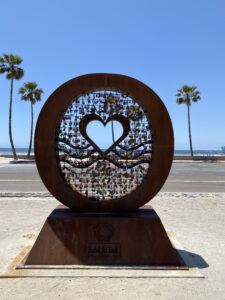 Love Lock Oceanside circle sculpture with open heart in the center and padlocks with initials