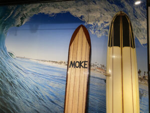 Painting at the California Surf Museum of a huge wave and two old-style surfboards
