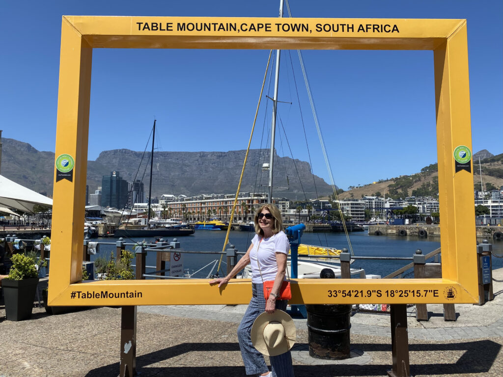 Giant Yellow Picture Frame with me in foreground and Table Mountain in the center of the frame at V & A Harbor