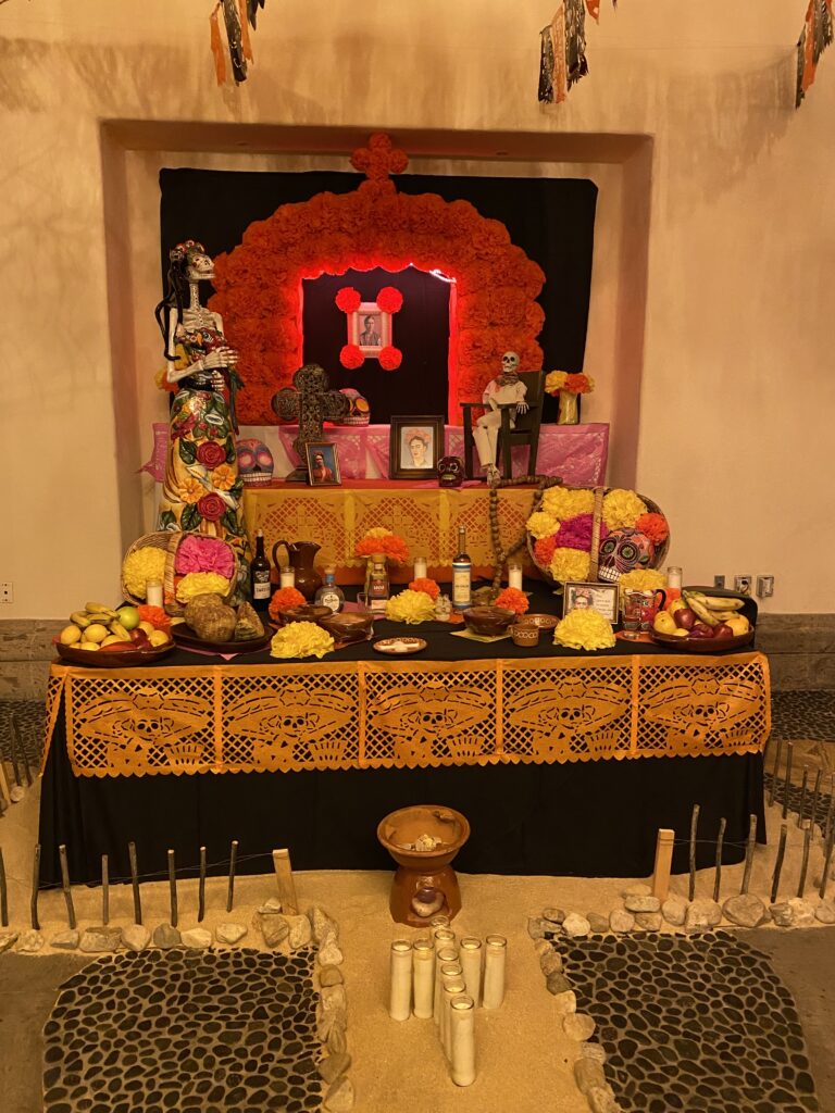Hacienda del Mar altar for Dia De Los Muertos Celebration with flowers, fruit, candles, and beverages